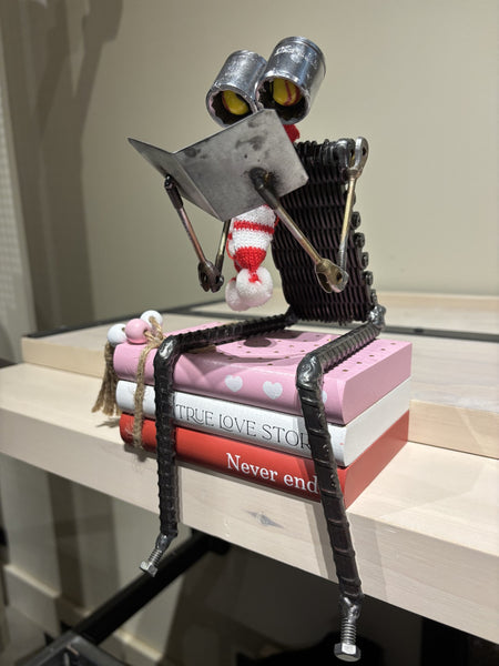 True Love -  Love Story Bot by R. Nelson features a reading robot sitting on stack of books.